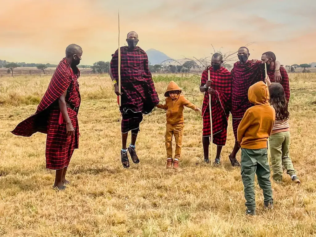 The warriors Maasai Tribe of the Serengeti jumping to the Adumu dance with Kids on Safari.