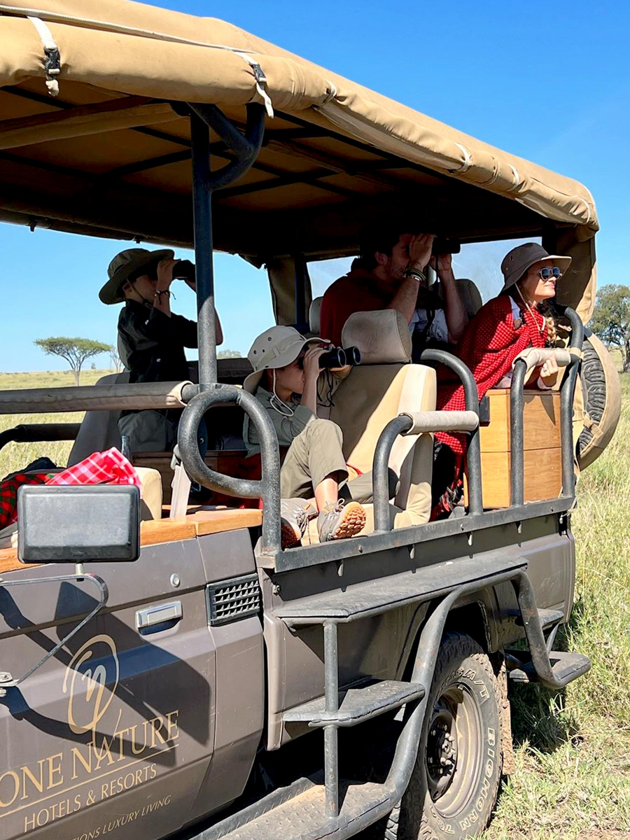 Kids on safari, sighting wildlife on a game drive in the Serengeti, Tanzania.