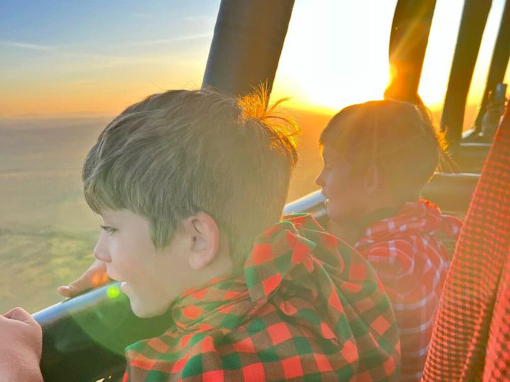 Kids on on a balloon safari mesmerized by the Serengeti landscape in Tanzania.