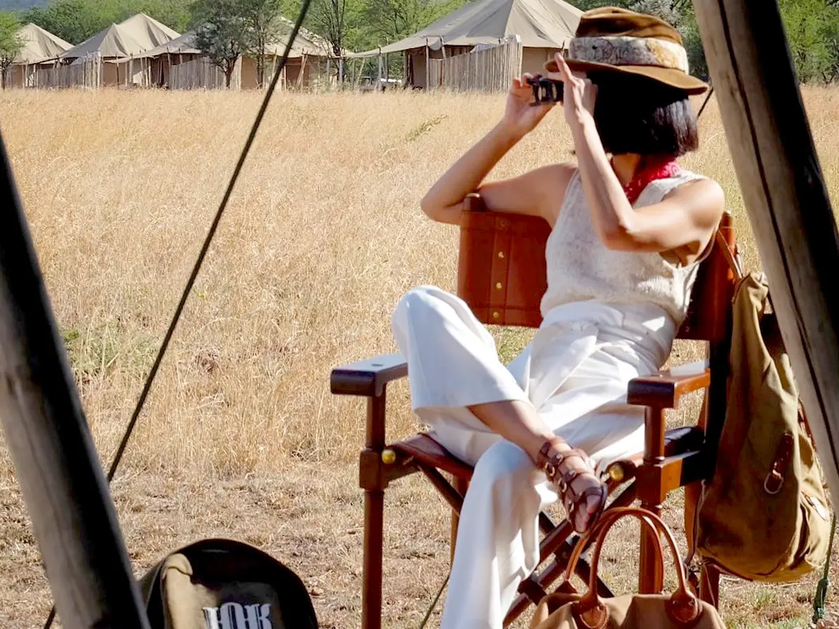 A woman enjoying the distant view of the Serengeti in a white shirt, an essential packing color on an African Safari.