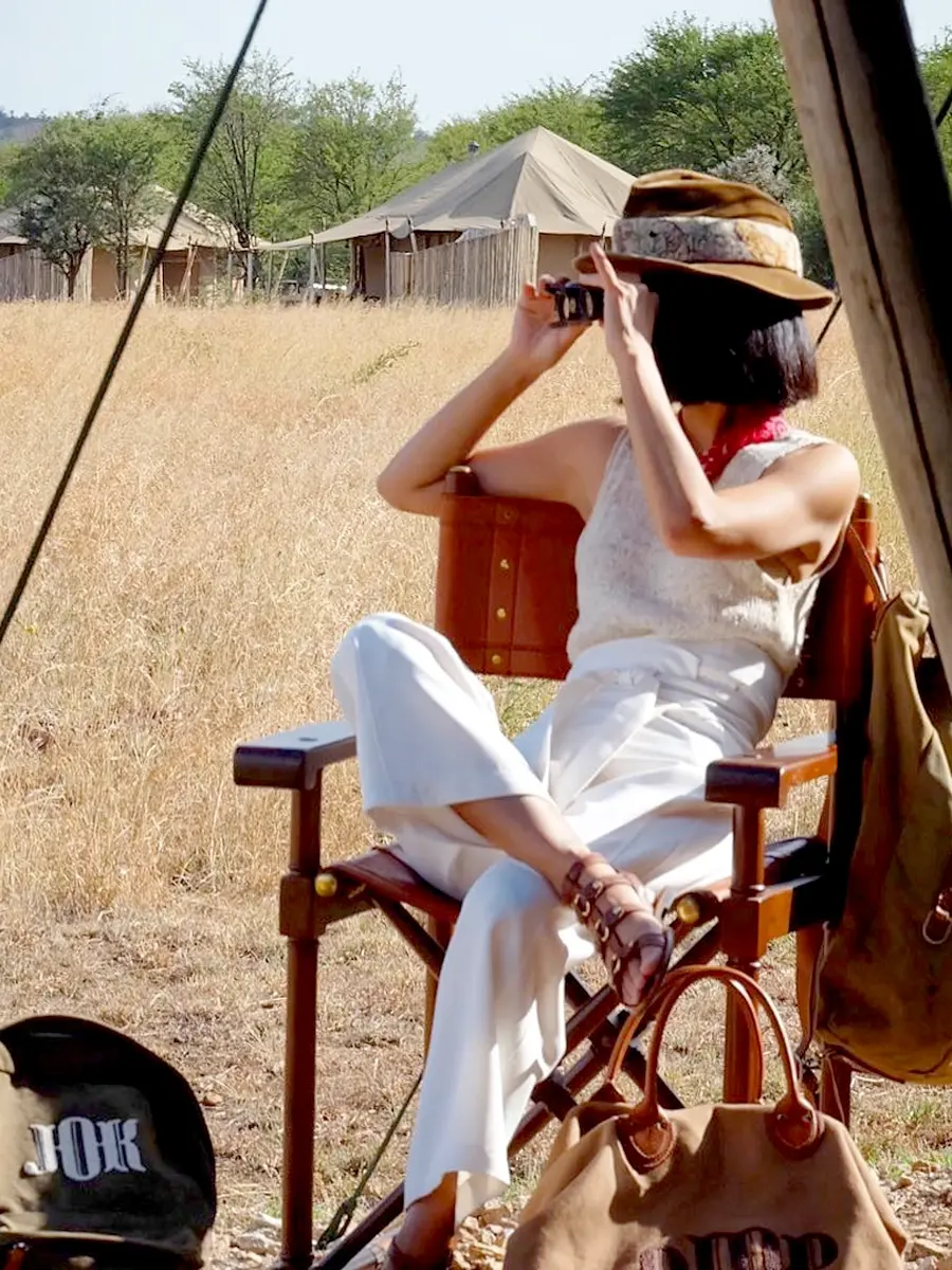 A woman enjoying the distant view of the Serengeti in a white shirt, an essential packing color on an African Safari.