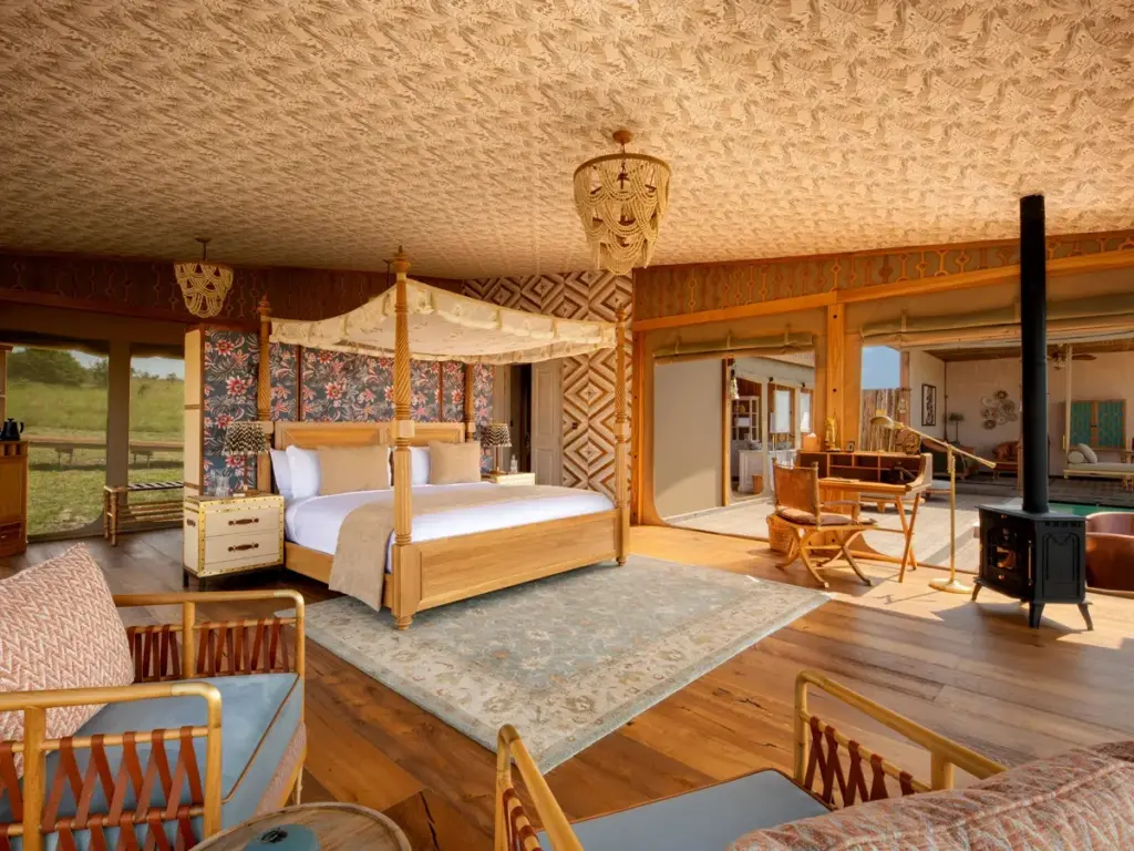 One-bedroom villa at One Nature Mara River Lodge featuring a canopy bed and a wood-burning stove.