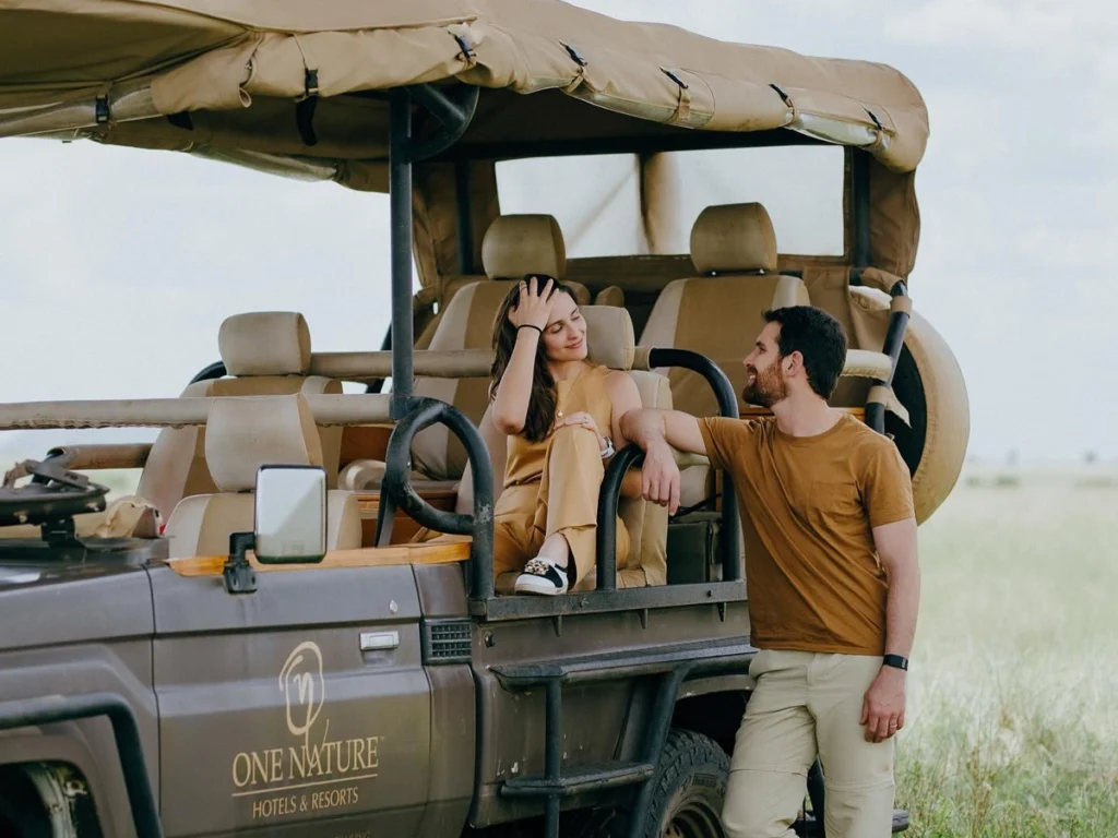 Safari Adventure Experience: A safari vehicle on the vast Serengeti plains with a majestic lion in the foreground.