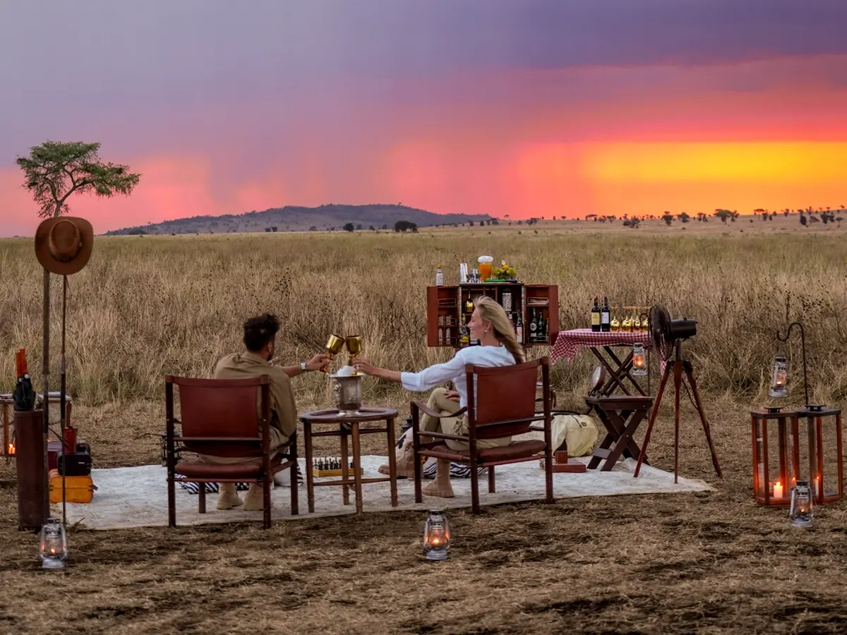 A couple toasting drinks at a private sundowner setup in the Serengeti during the New Year's holiday safari